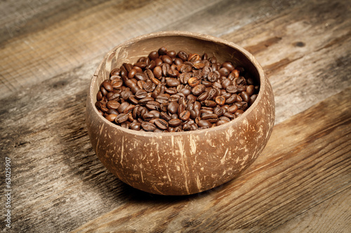 Wooden cup with coffee-beans on wooden table
