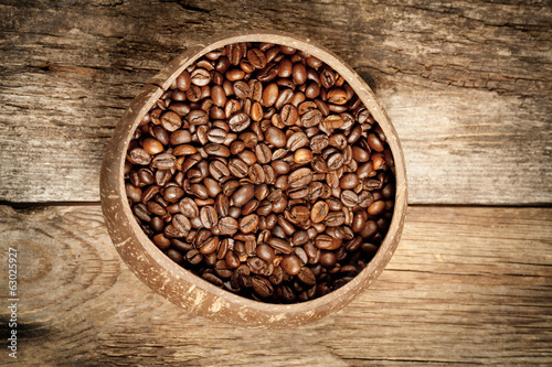 Wooden cup with coffee-beans on wooden table