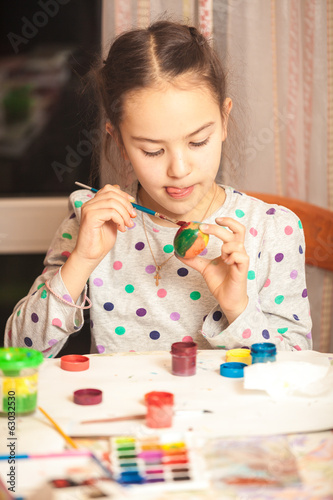 Closeup photo of little diligent girl painting easter egg