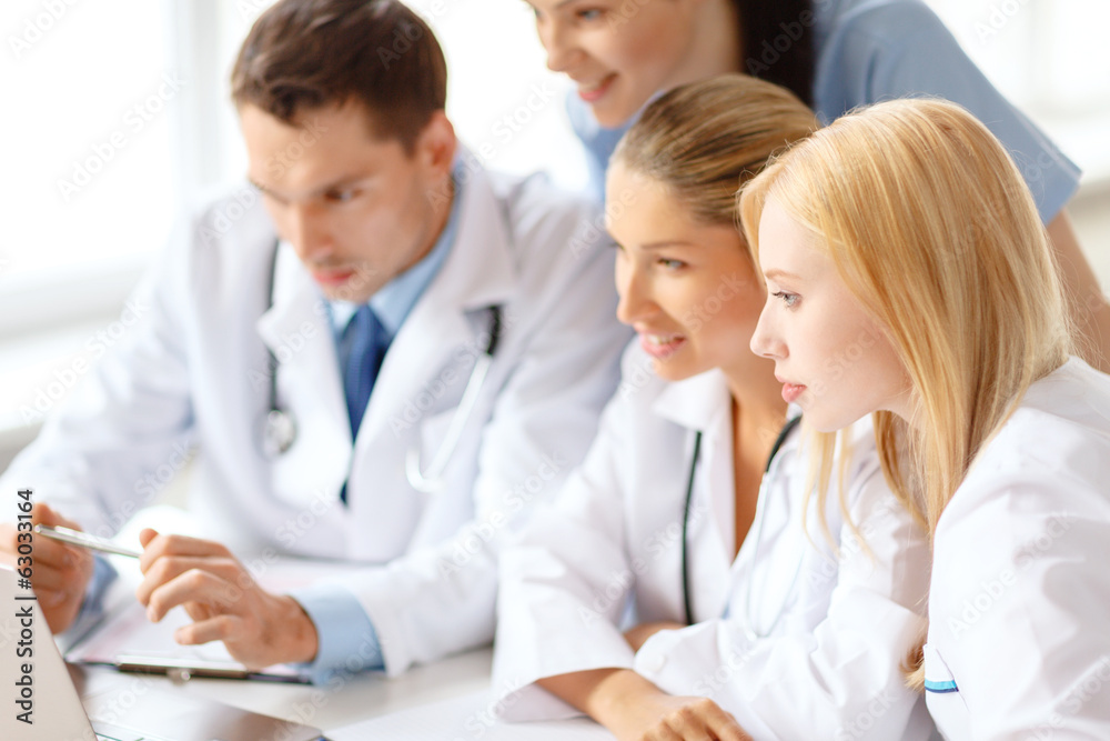 group of doctors looking at laptop computer group of doctors looking at laptop computer