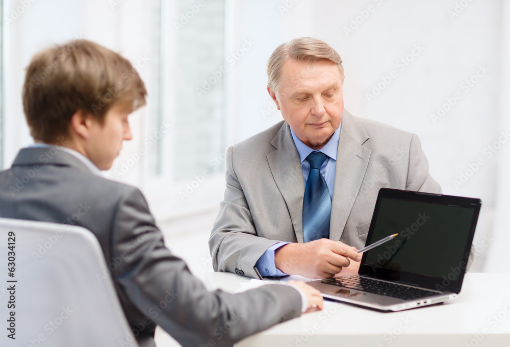 older man and young man with laptop computer older man and young man with laptop computer
