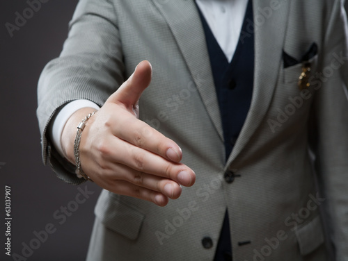 Businessman in suit offering to shake hands.