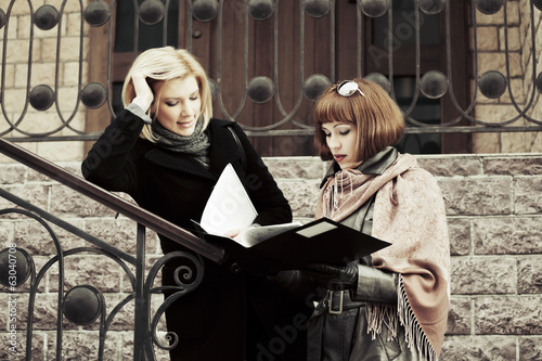 Two young business women with financial folder