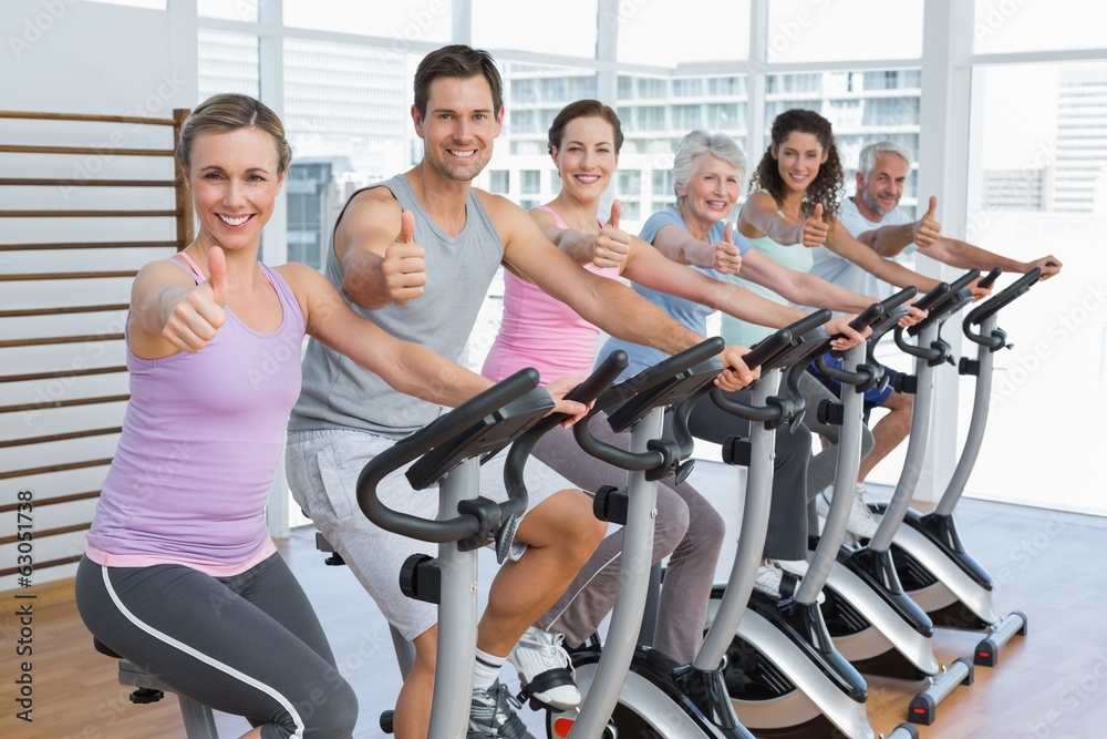 People working out at spinning class while gesturing thumbs up People working out at spinning class while gesturing thumbs up