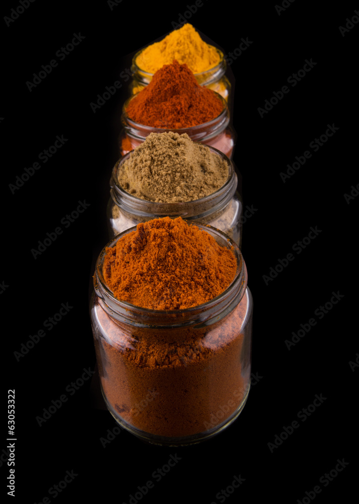 Mix powdered spices in glass container over black background Mix powdered spices in glass container over black background