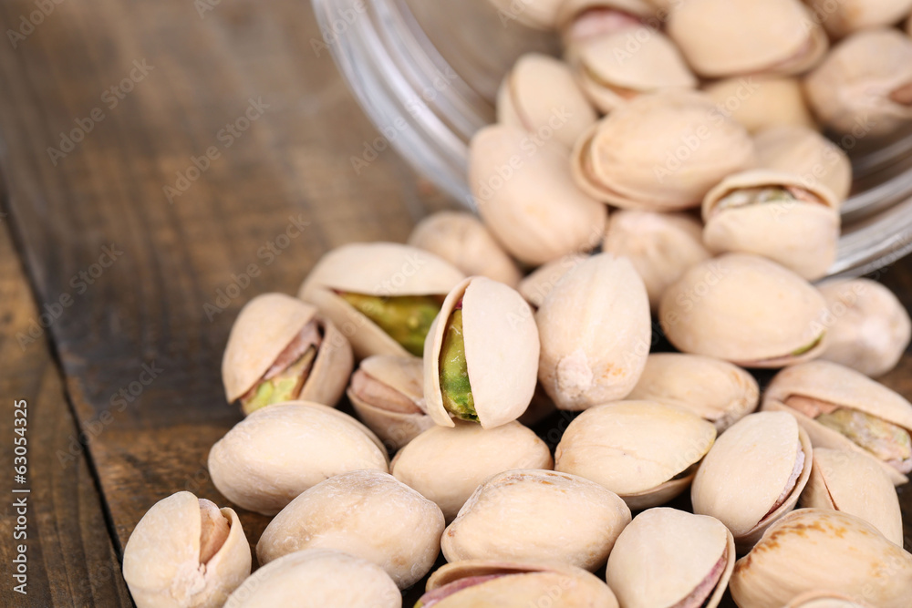 Pistachio nuts in glass jar on table close up
