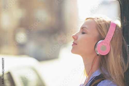 Foto Young woman listening music in headphones in the city