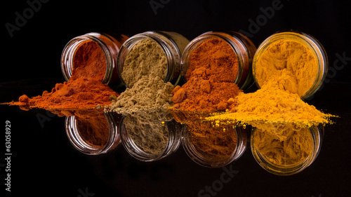 Mix powdered spices in glass container over black background