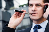 Businessman is smoking electronic cigarette outdoor