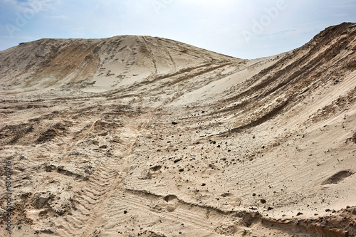 Sand hills over blue sky with car tires footprint
