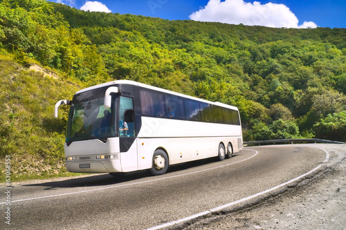 Tourist bus traveling on road among mountains photo