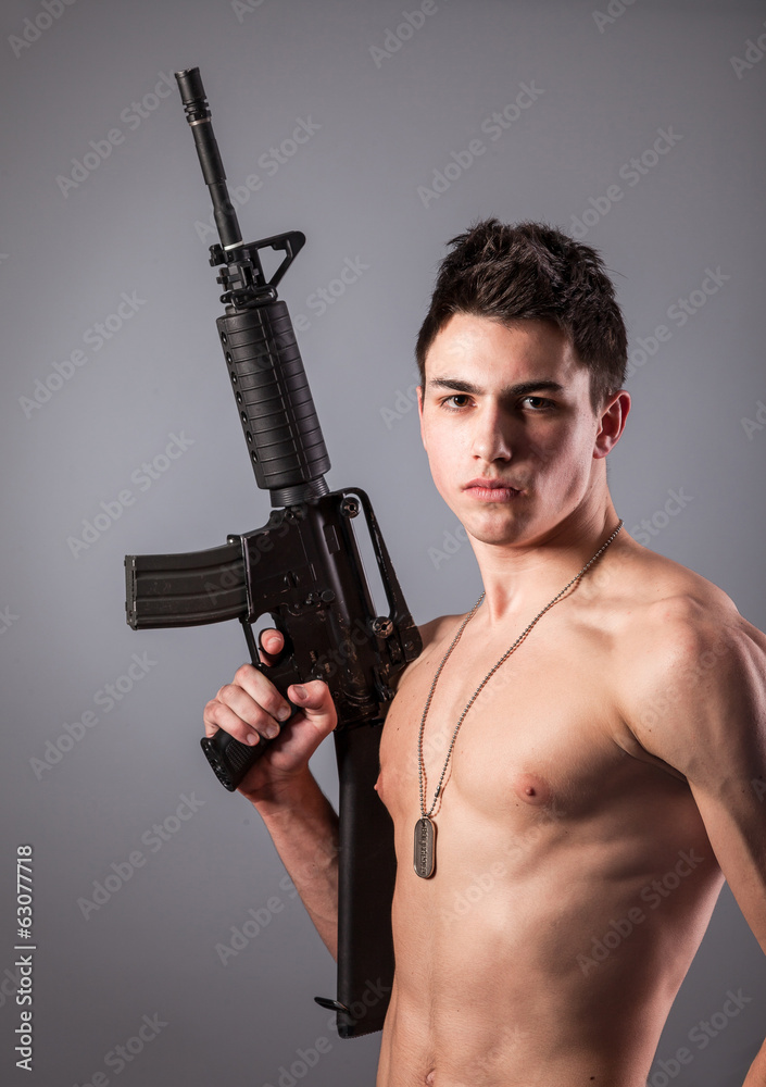 Handsome bare-chested soldier is holding a rifle Handsome bare-chested soldier is holding a rifle