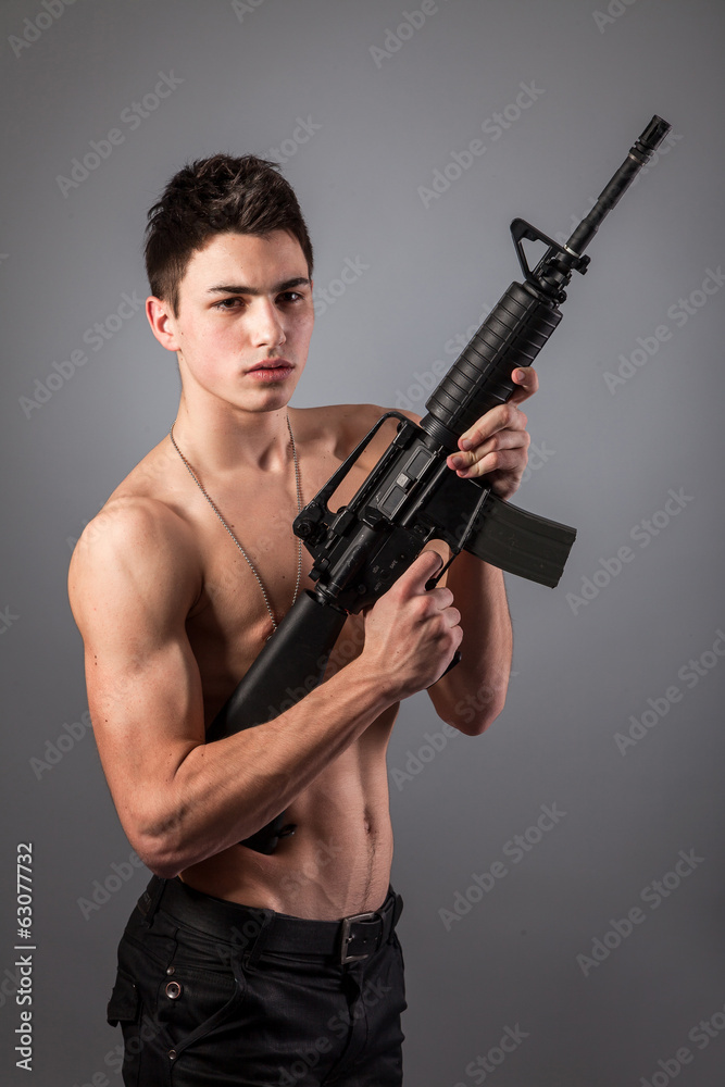 Handsome bare-chested soldier is holding a rifle Handsome bare-chested soldier is holding a rifle