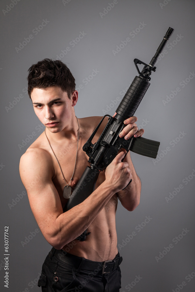 Handsome bare-chested soldier is holding a rifle Handsome bare-chested soldier is holding a rifle