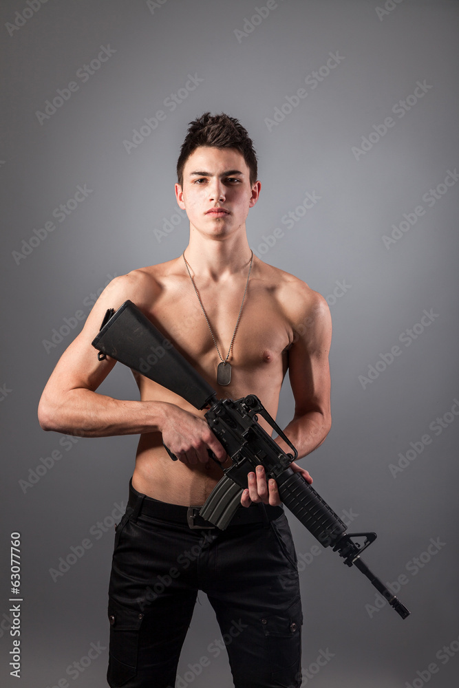 Handsome bare-chested soldier is holding a rifle Handsome bare-chested soldier is holding a rifle