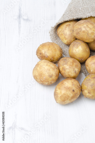 new potatoes in a sack on a white background, vertical