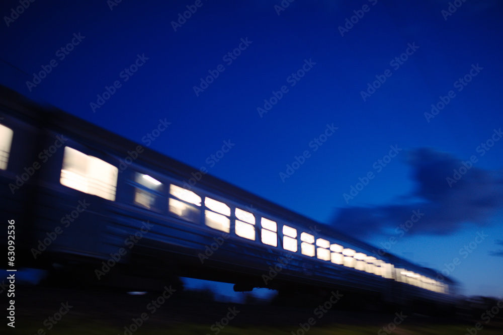 Fototapeta premium Oświetlony pociąg przejeżdżający w nocy