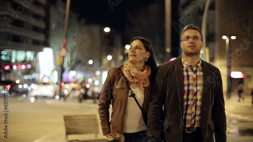 Young couple walking in night city, steadycam shot