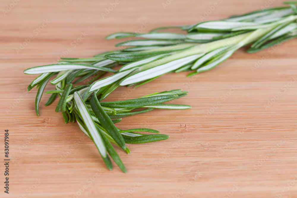 Rosemary branch on a chopping wooden board Rosemary branch on a chopping wooden board