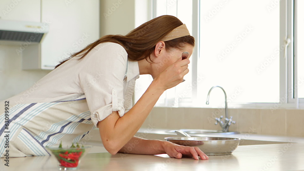Woman stirring and tasting something in frying pan at the Woman stirring and tasting something in frying pan at the
