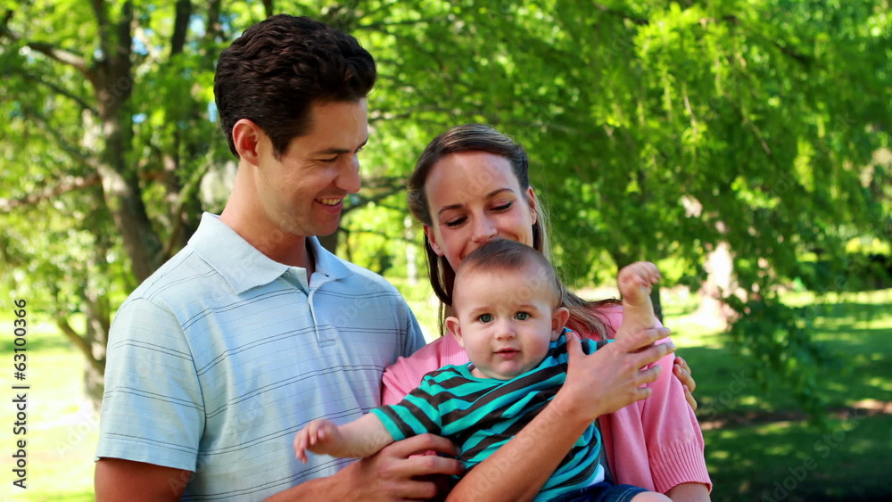 Young couple holding their baby son smiling at camera Young couple holding their baby son smiling at camera