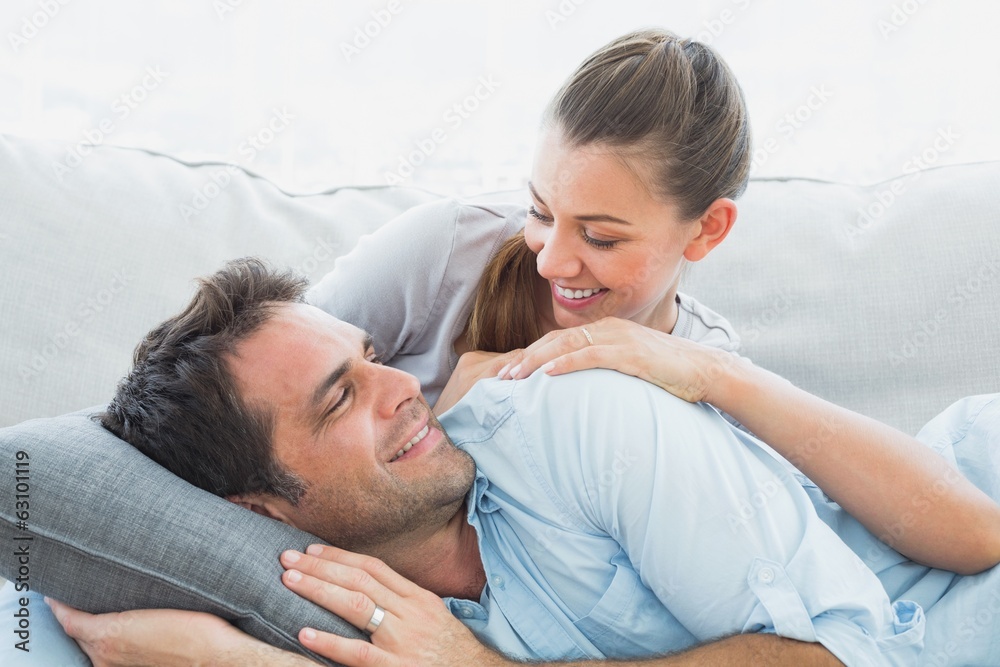 Cheerful couple relaxing on their sofa smiling at each other Cheerful couple relaxing on their sofa smiling at each other