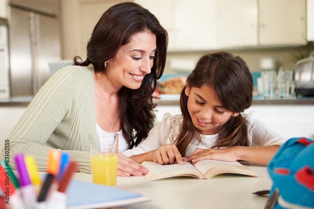 Mother Helping Daughter With Reading Homework At Table Mother Helping Daughter With Reading Homework At Table