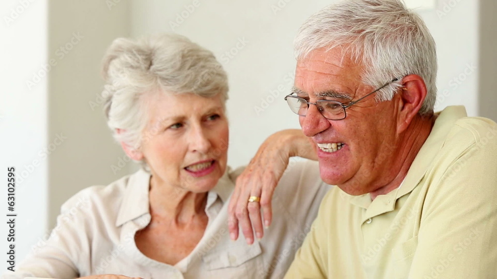 Senior couple sitting at the table using tablet pc