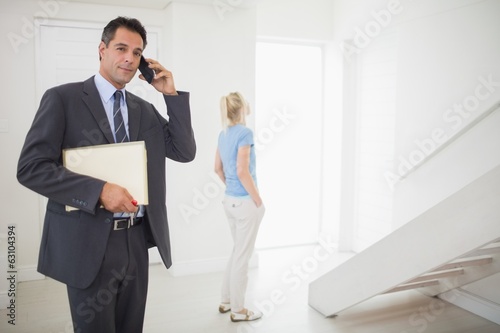 Real estate agent on call with blurred woman in background © WavebreakmediaMicro
