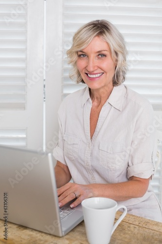 Smiling casual mature woman using laptop at home
