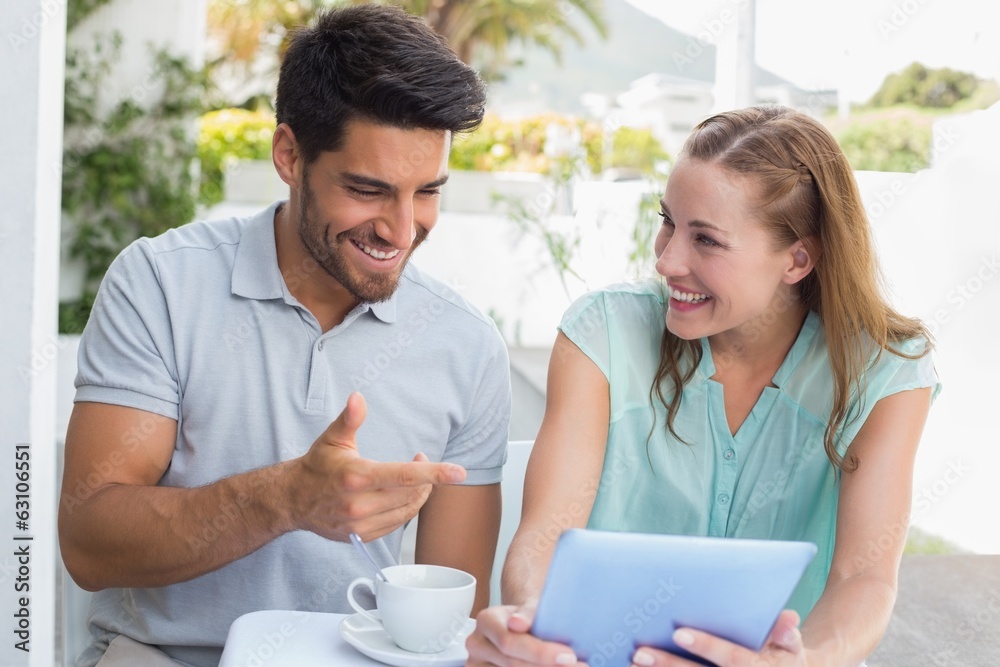 Happy couple with coffee cup using digital tablet at café Happy couple with coffee cup using digital tablet at café