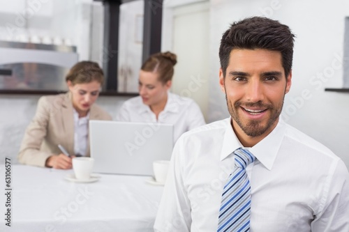 Smiling businessman with colleagues at office desk © lightwavemedia