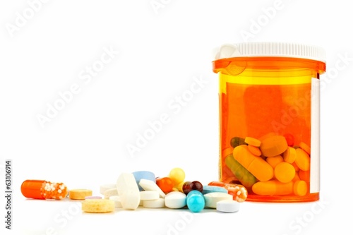 Pill bottle with pile of varied medicine over white