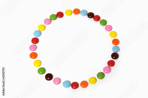 circle of colorful chocolate candies spread on white background