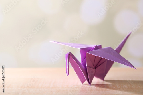 Origami crane on wooden table, on light background