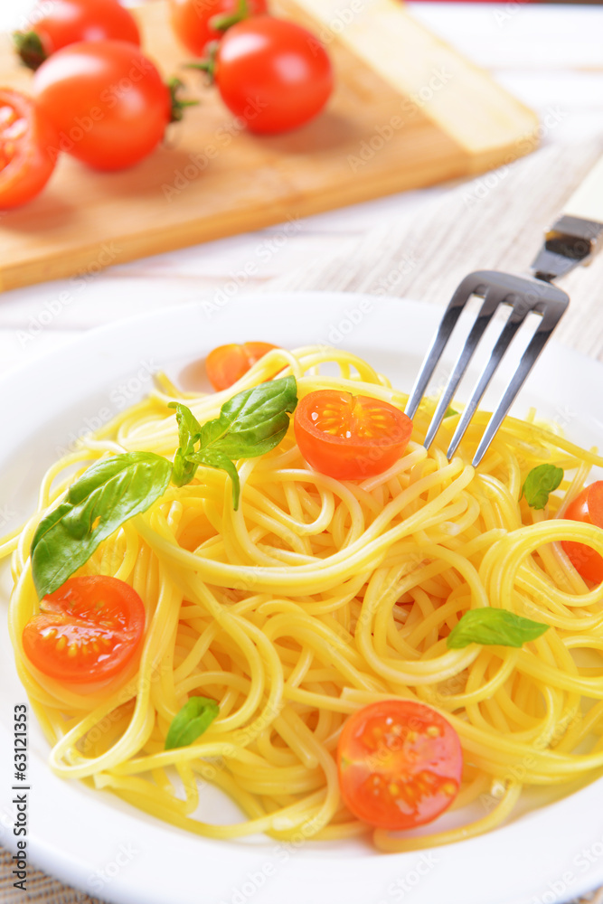 Delicious spaghetti with tomatoes on plate on table close-up Delicious spaghetti with tomatoes on plate on table close-up