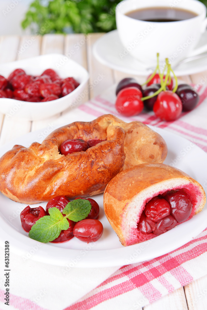 Fresh baked pasties with cherry on plate on table close-up