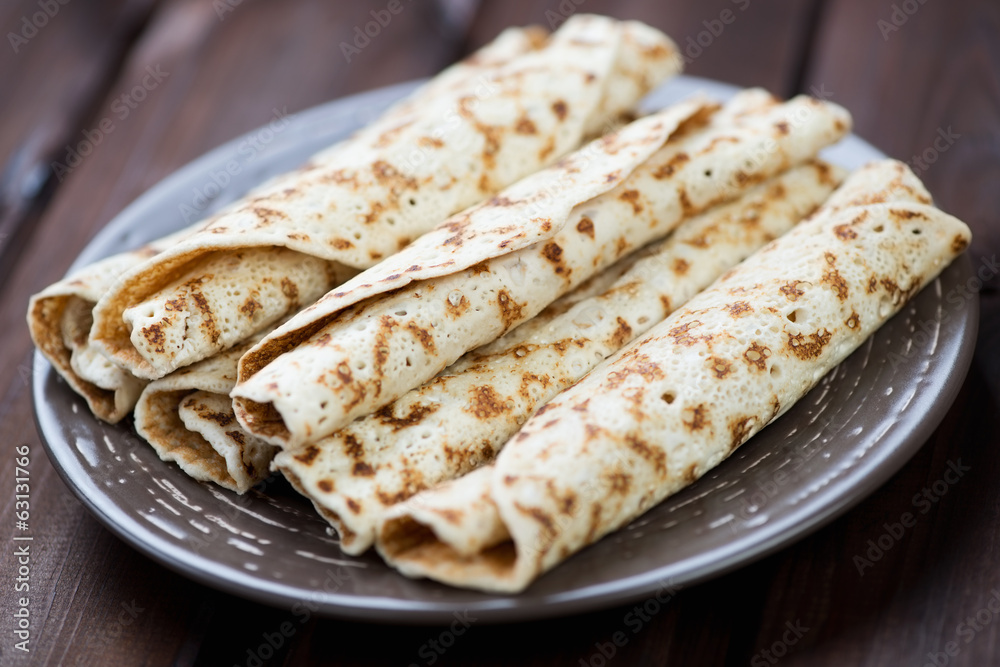 Glass plate with rolled stuffed crepes, horizontal shot