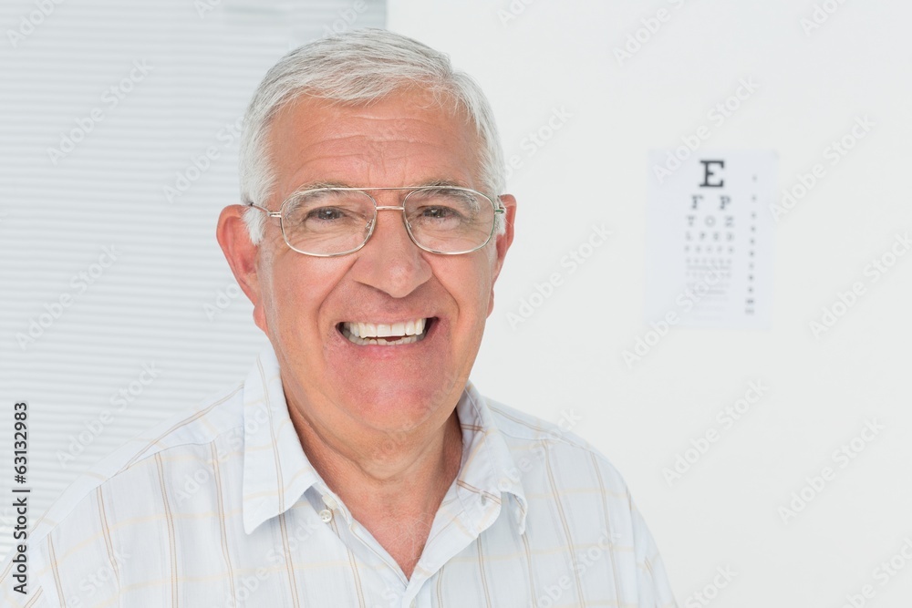 Portrait of a smiling senior man with eye chart in background