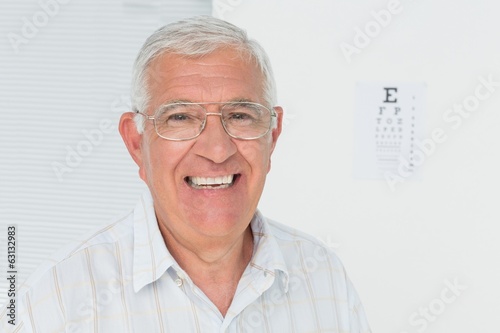 Fototapeta Naklejka Na Ścianę i Meble -  Portrait of a smiling senior man with eye chart in background