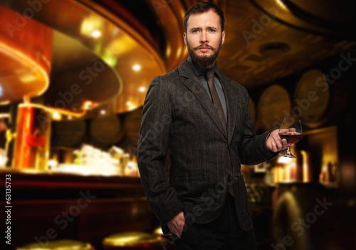 Handsome well-dressed man with glass of beverage 