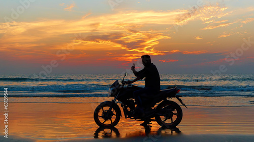 Motorcyclist at sunset on the beach.