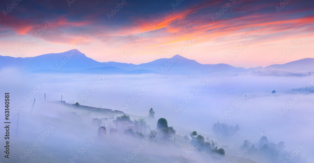 Silhouettes of the mountains and village in the morning mist.