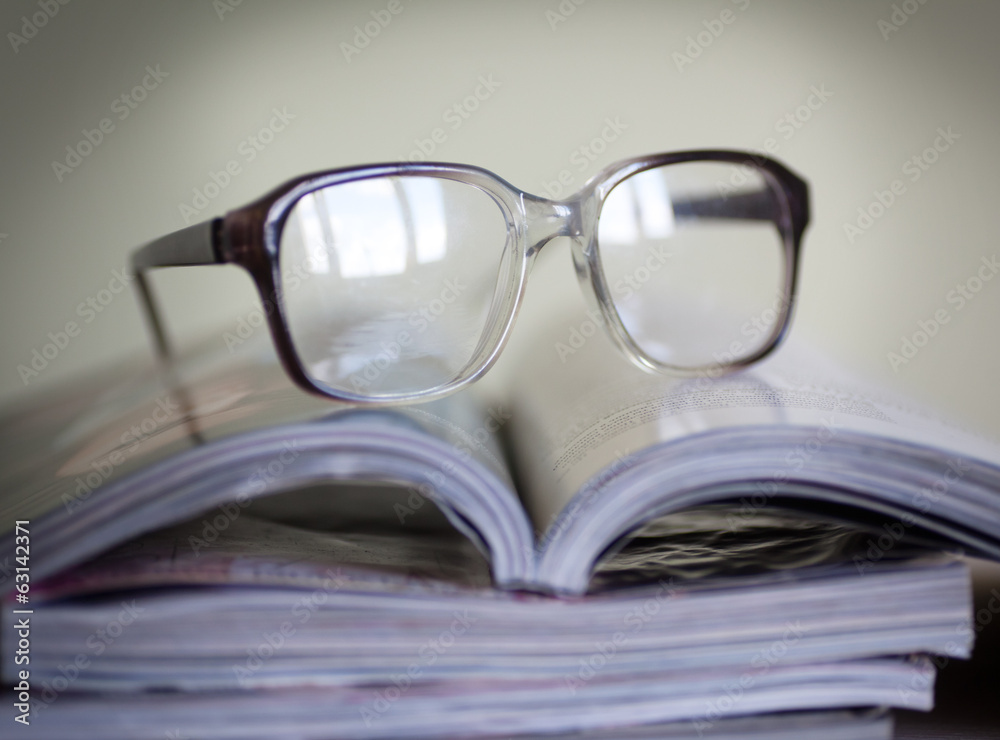 glasses for reading on a stack of magazines, in soft focus glasses for reading on a stack of magazines, in soft focus