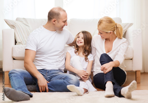 parents and little girl sitting on floor at home