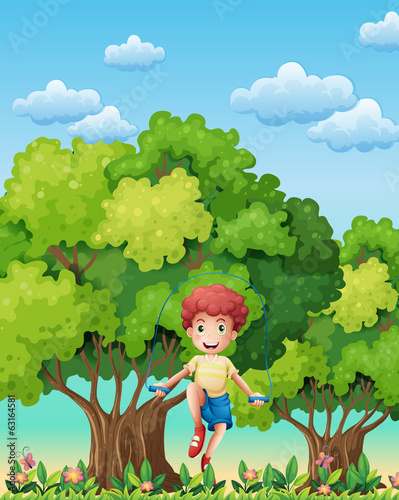 A boy playing with the skipping rope near the trees