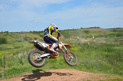 Fototapeta Naklejka Na Ścianę i Meble -  Motocross rider on a motorcycle spectacularly lands on a edge of