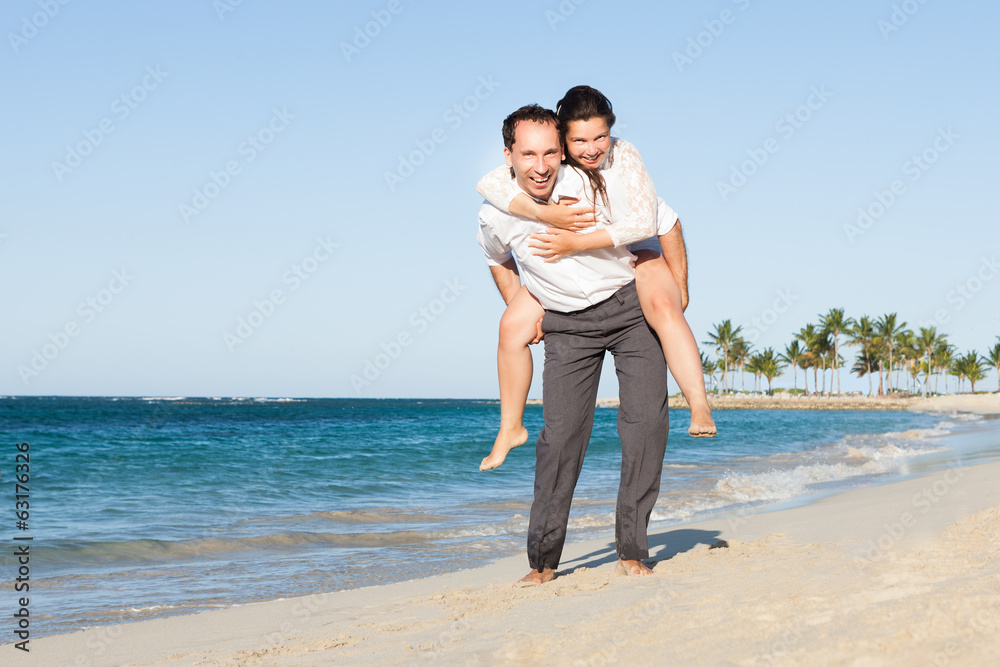 Man Giving Piggyback Ride To Woman At Beach