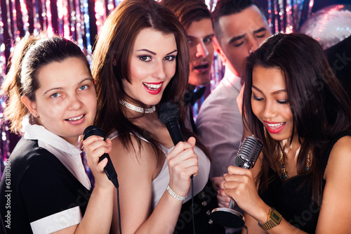 Friends Singing Into Microphones At Karaoke Party