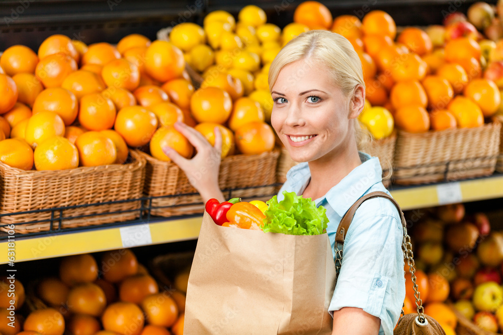 Obraz premium Choosing oranges girl hands bag with fresh vegetables